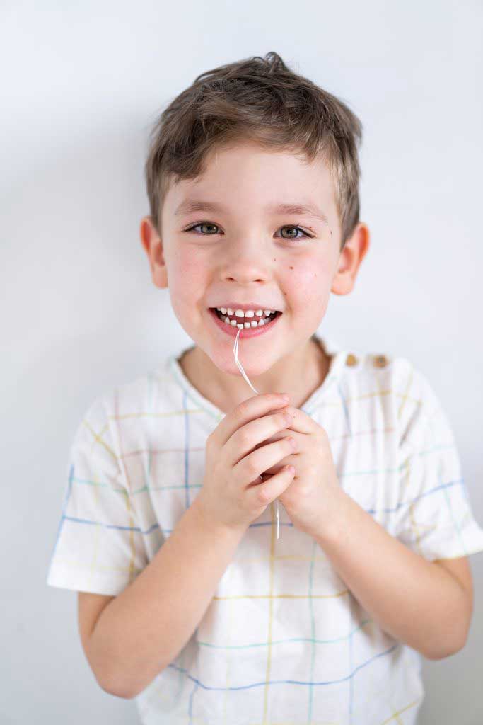 cute-boy-pulling-loose-tooth-using-a-dental-floss-2023-11-27-05-12-26-utc-683x1024